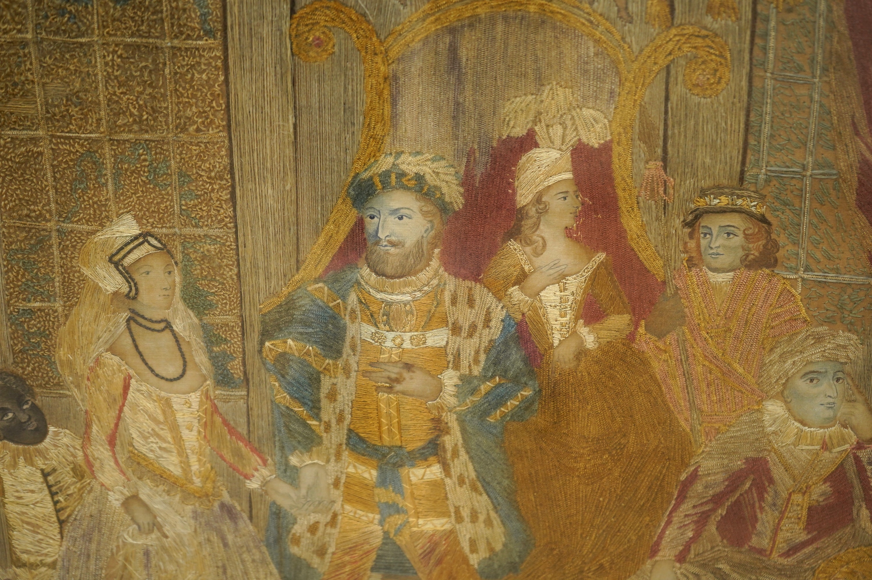 A large unusual Regency framed silk worked embroidery depicting Henry VIII in court with three courtiers and a blackamoor servant holding the dress of a young female courtier as she enters, worked mainly in long stem sti